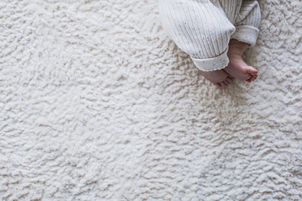 Babyfüße, Newbornshooting, Babyshooting, Baby liegt auf einem Teppich